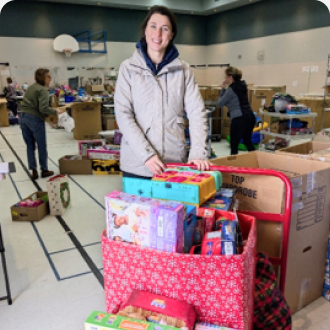 MITY Inc employee standing with a cart loaded with toys